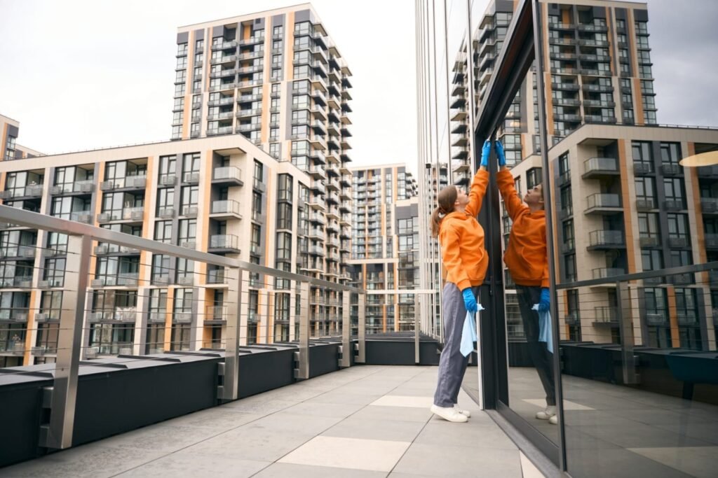 Empleada de limpieza limpiando los vidrios exteriores, fondo de edificios de la ciudad